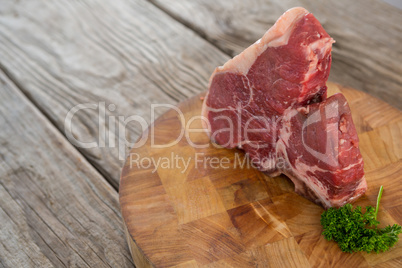 Sirloin chop and corainder leaves on wooden tray against wooden background