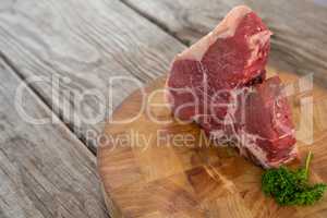 Sirloin chop and corainder leaves on wooden tray against wooden background