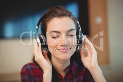 Female graphic designer listening music on headphones