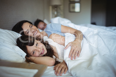 Mother and daughter laughing in bed