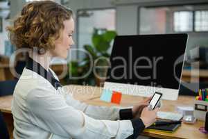 Woman sitting at desk and using mobile phone