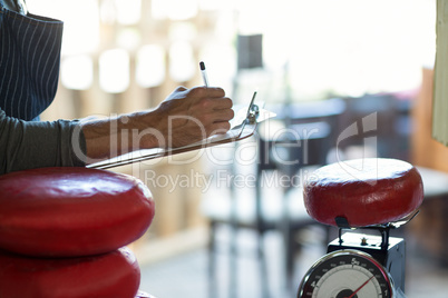 Mid section of salesman writing on clipboard at counter