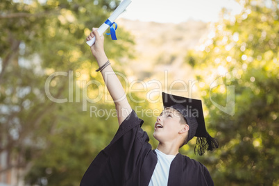 Excited graduate schoolboy with degree scroll in campus