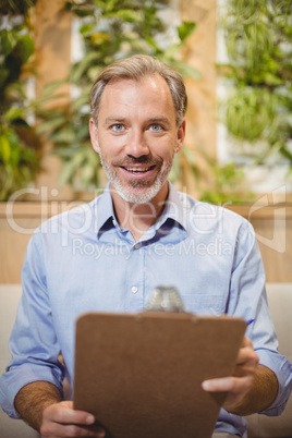 Smiling doctor holding clipboard in clinic