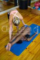 Trainer assisting a woman while practicing pilates