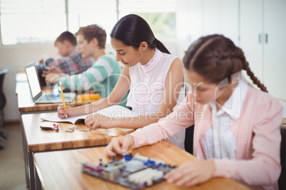 Smiling schoolgirl doing homework in classroom