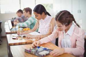 Smiling schoolgirl doing homework in classroom