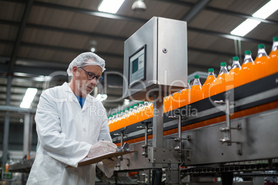 Factory engineer maintaining record on clipboard in factory