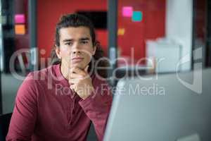 Male executive sitting with on chin in office