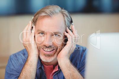 Male graphic designer listening music on headphones