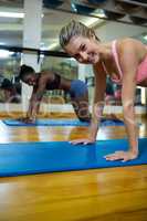 Portrait of two fit women doing stretching exercise on mat