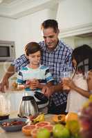 Father serving smoothie to his kids in kitchen