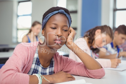 Thoughtful schoolgirl sitting in classroom