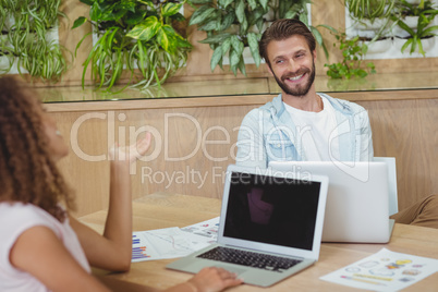 Business executives interacting while using laptop