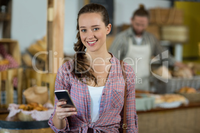 Portrait smiling woman using mobile phone at counter