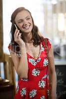 Smiling woman talking on mobile phone at counter