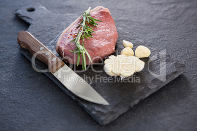 Sirloin chop, knife and garlic on slate plate