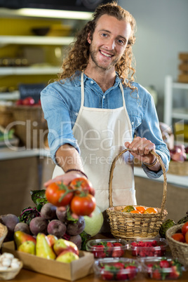 Smiling vendor offering tomatoes in the grocery store