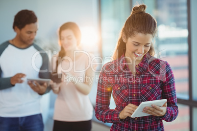 Female executive using digital tablet with her colleagues in background
