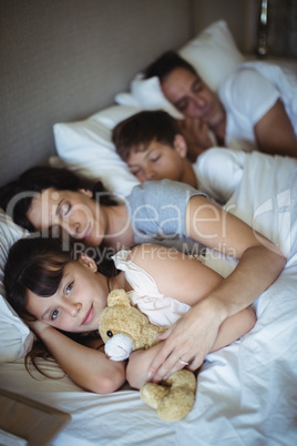 Parents and kids sleeping on bed