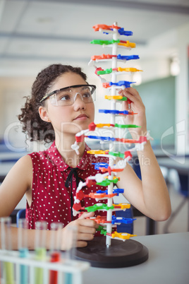 Attentive schoolgirl experimenting molecule model in laboratory