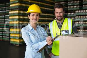 Factory workers maintaining record on clipboard in factory