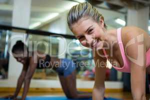 Portrait of smiling fit women doing stretching exercise on mat