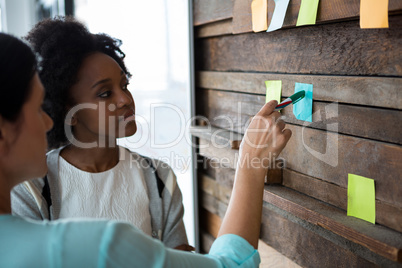 Female graphic designer writing on sticky notes