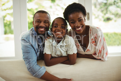 Portrait of parents and son leaning over sofa in living room