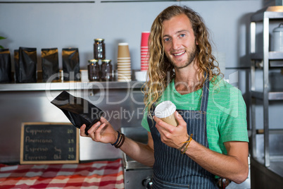 Portrait of male staff holding coffee cup and parcel bag at counter