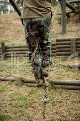 Low section of man climbing a rope during obstacle course