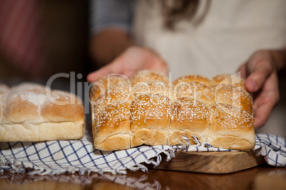 Mid-section of woman holding bread at counter