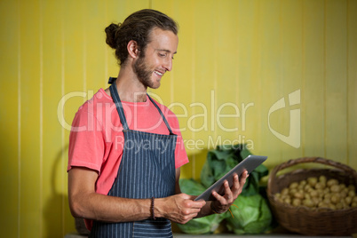 Smiling male staff using digital tablet in organic section