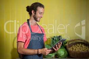 Smiling male staff using digital tablet in organic section