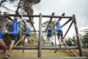 Fit people climbing monkey bars in bootcamp