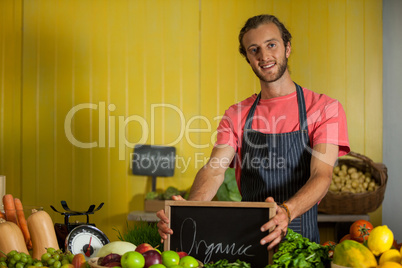 Portrait of male staff holding slate board in organic section