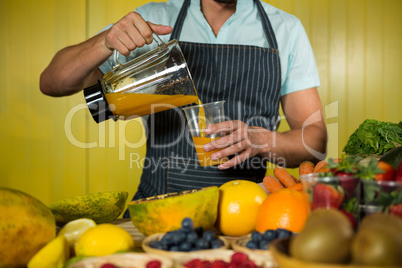 Male staff pouring juice into glass at counter