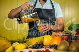 Male staff pouring juice into glass at counter