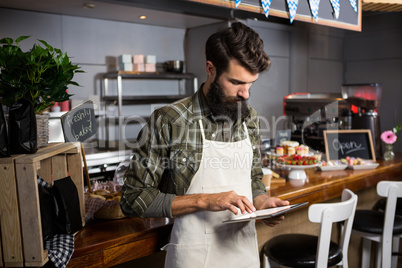 Male staff using digital tablet at counter