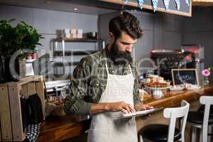 Male staff using digital tablet at counter
