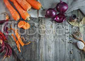 Fresh vegetables carrots and onions on a gray wooden surface