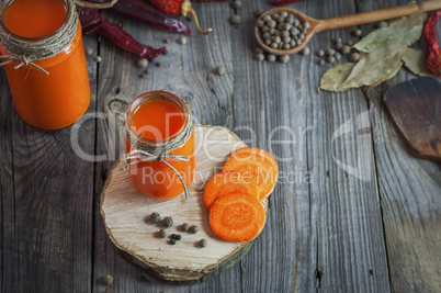Glass jars with juice on a gray wooden background