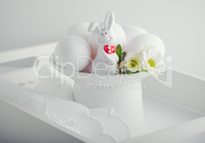 Eggs Rabbit and flowers on white surface