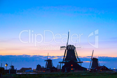 Silhouettes of Dutch mills near the lake at sunset