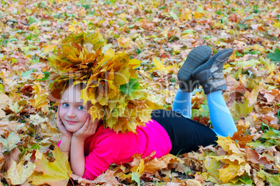 little girl with yellow leaves in the park