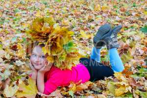 little girl with yellow leaves in the park