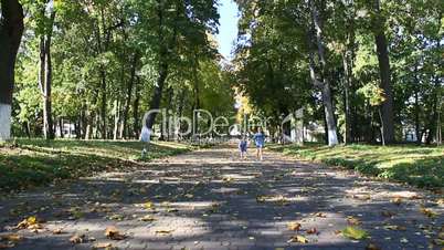 young happy sisters run in the autumnal park