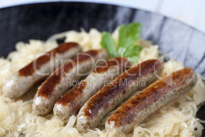 Nürnberger Bratwurst auf Kraut in einer Pfanne