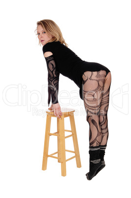 Woman in bodysuit standing on chair.