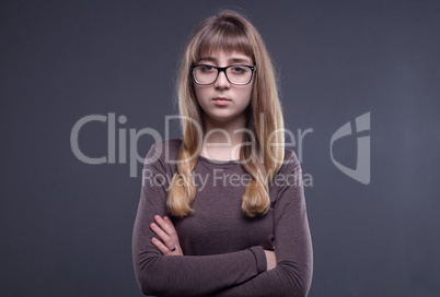 Teenage girl in glasses with arms crossed